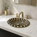 Bathroom sink with black and white striped basin and gold faucet on marble countertop.
