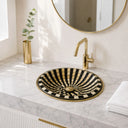 Bathroom vanity with a black and gold sink and gold faucet.