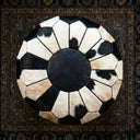 Round black and white patterned rug on a dark textured surface