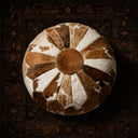 Handcrafted genuine cowhide leather pouf ottoman in rich brown & white. Premium barrel-design seating for luxury living rooms. Artisan-made, versatile home décor.