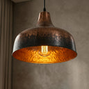 Handcrafted brass pendant light hanging above a kitchen island with warm reflective lighting.