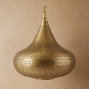 Handmade Moroccan brass pendant light featuring intricate pierced metalwork and warm ambient illumination casting decorative shadow patterns.