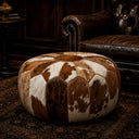 Handcrafted genuine cowhide leather pouf ottoman in rich brown & white. Premium barrel-design seating for luxury living rooms. Artisan-made, versatile home décor.