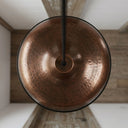 Handmade hammered brass pendant light illuminating a dining area with warm ambient lighting.