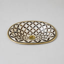 Oval bone inlay sink with black and white geometric diamond pattern and brass rim, displayed against neutral gray background showing overhead view of handcrafted design