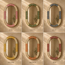 Six oval mirrors with decorative frames in different colors on a beige wall.