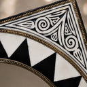 Decorative tile with black, white, and gold geometric pattern